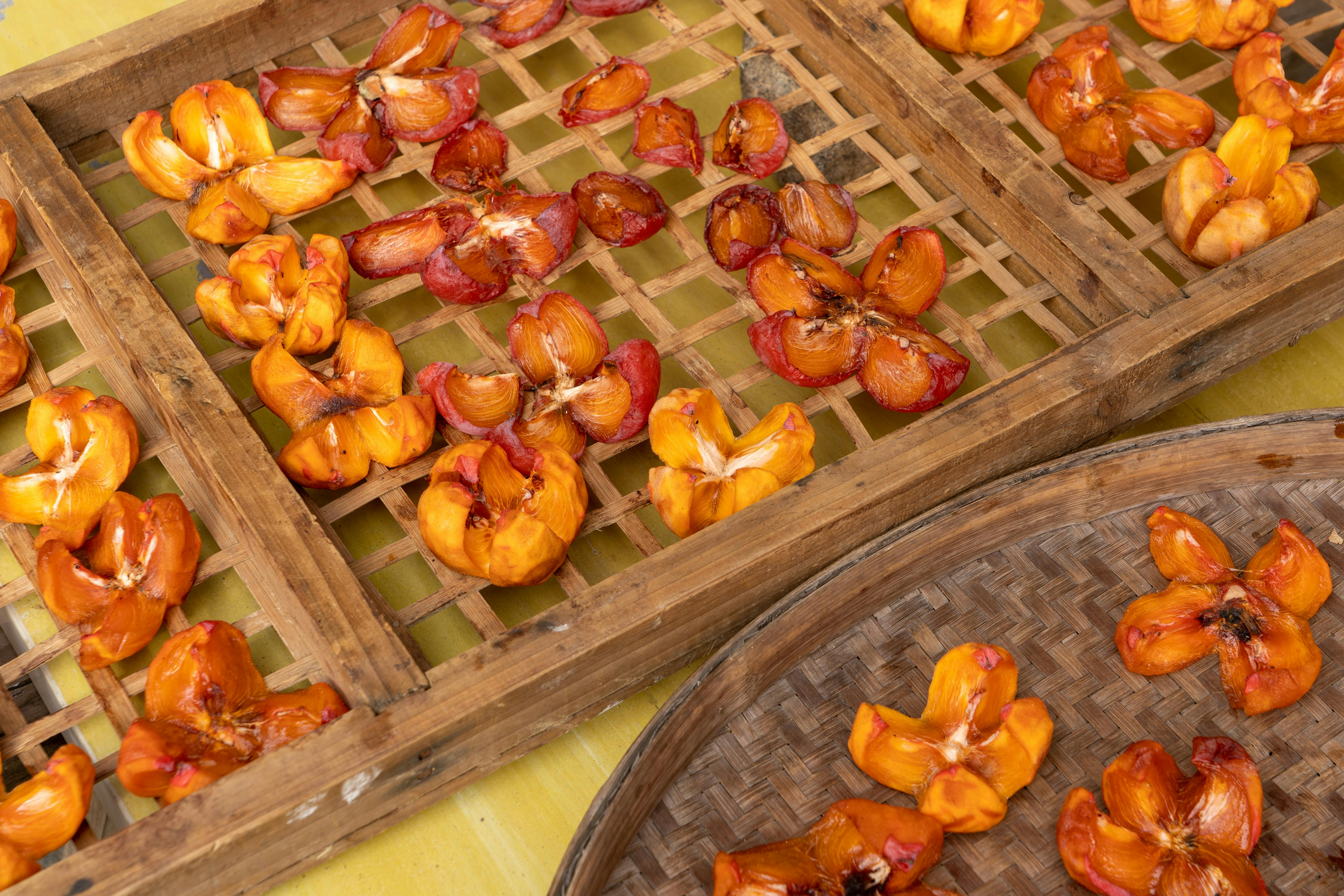 Sun-dried fruits laid out on wooden trays for preservation
